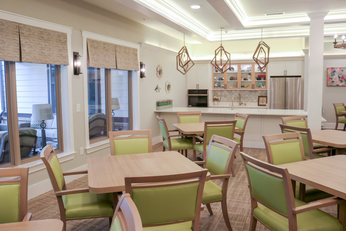 A modern dining area with green-accented chairs, geometric lighting fixtures, and a cozy ambiance.