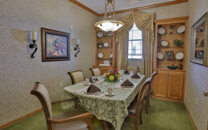 A cozy dining room with an elegant table setting, featuring decorative plates and a floral centerpiece.