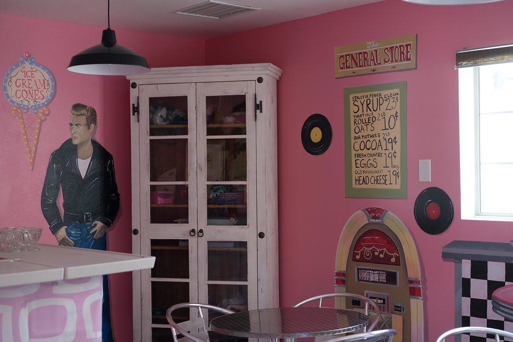 A retro-themed diner with pink walls, a jukebox, and vintage decor.