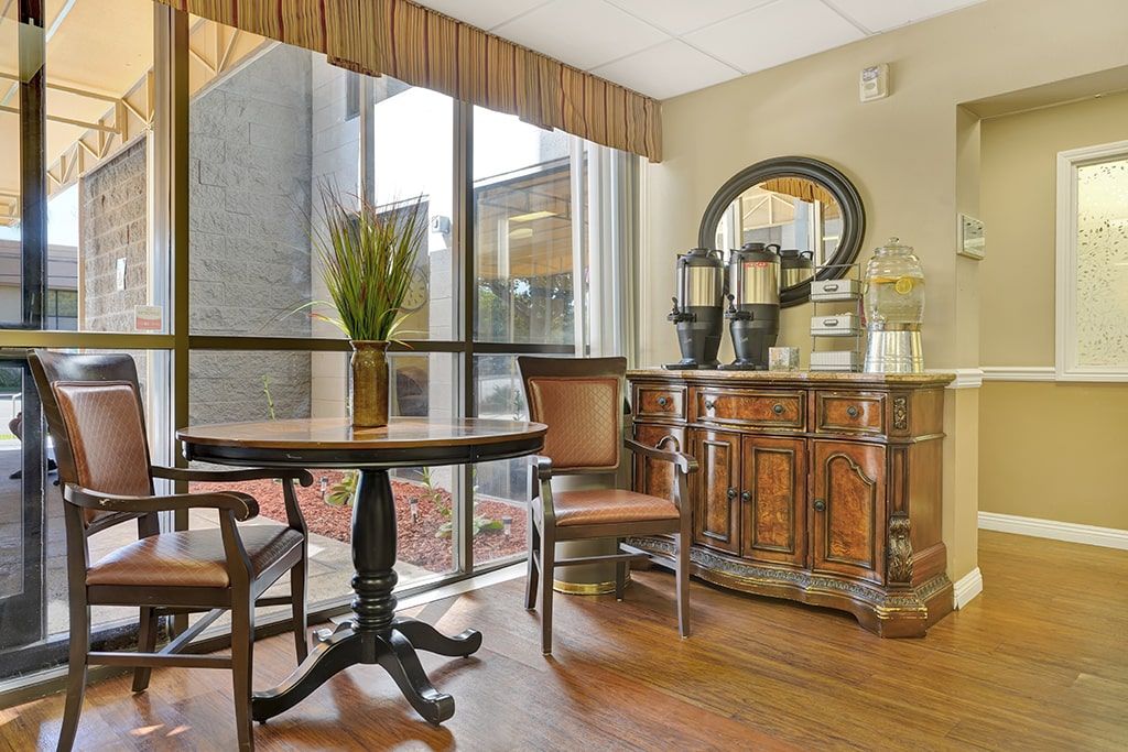 A cozy hotel lobby with a coffee station and seating area near a large window.