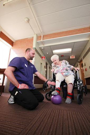 A healthcare professional assists an elderly person in a physical therapy exercise aimed at improving mobility and strength.