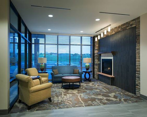 A modern lounge area featuring comfortable seating, a stylish fireplace, and large windows that offer a view outside.