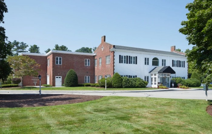 A brick building with large windows and a landscaped lawn on a clear day.