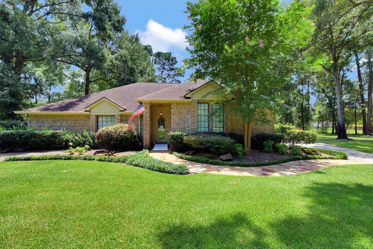 A well-maintained suburban house with a lush green lawn and surrounding trees.