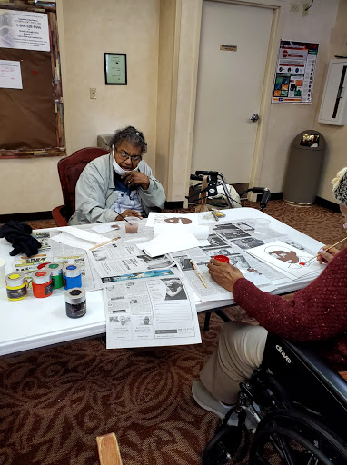 Two individuals engaged in a creative art activity, working on projects at a table filled with various materials.