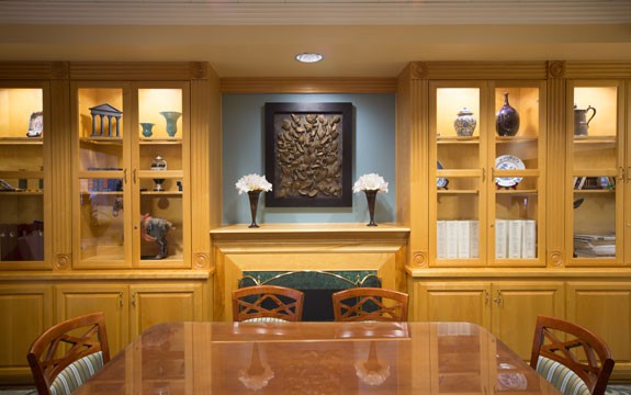 A cozy dining room with wooden cabinets and display shelves featuring decorative vases and artwork.