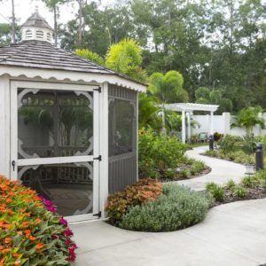 A picturesque garden with a gazebo and winding pathway surrounded by lush greenery and colorful flowers.