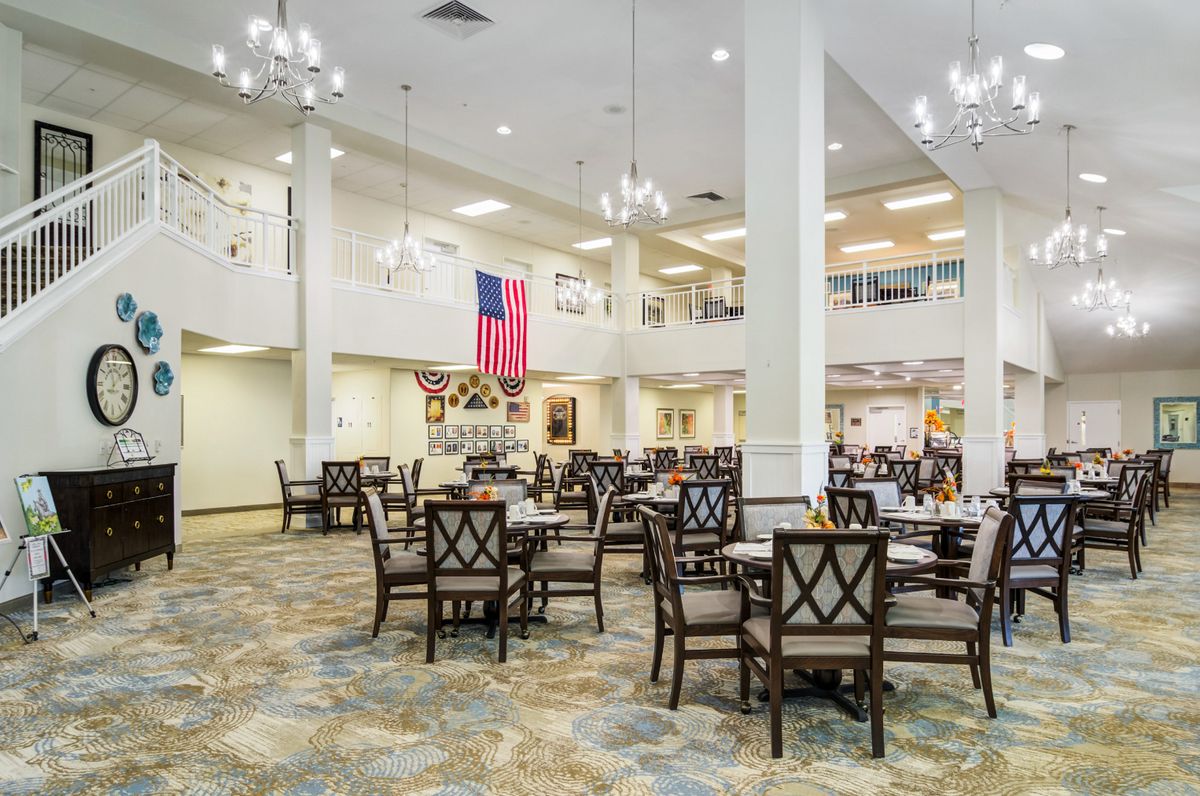 A spacious dining area with tables, chairs, chandeliers, and flags on display.