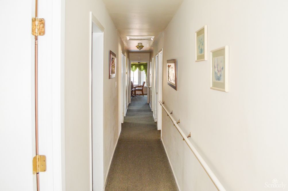 A long, narrow hallway with carpet flooring and decorated with paintings on the walls.