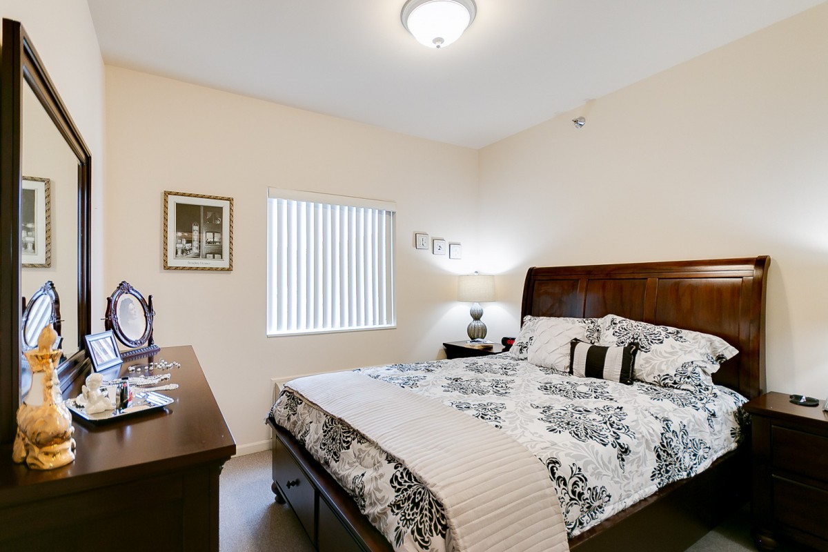 A cozy bedroom with a patterned bedspread, wooden furniture, and soft lighting.