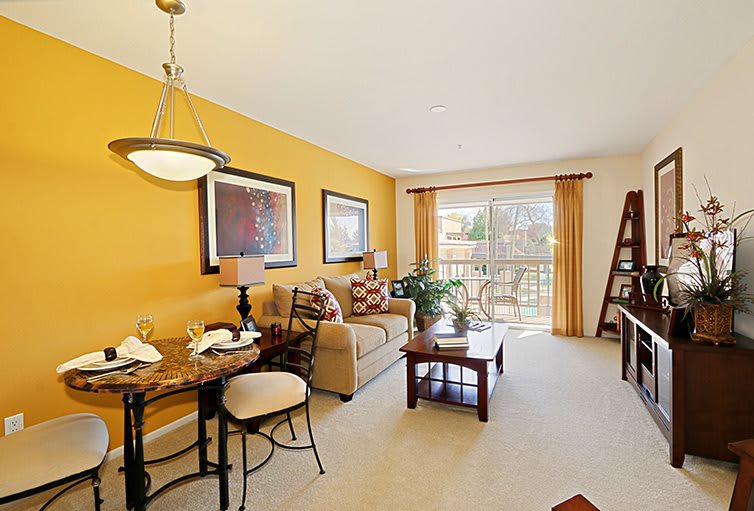 Cozy living room with warm colors, featuring a sofa, dining table, and large windows.