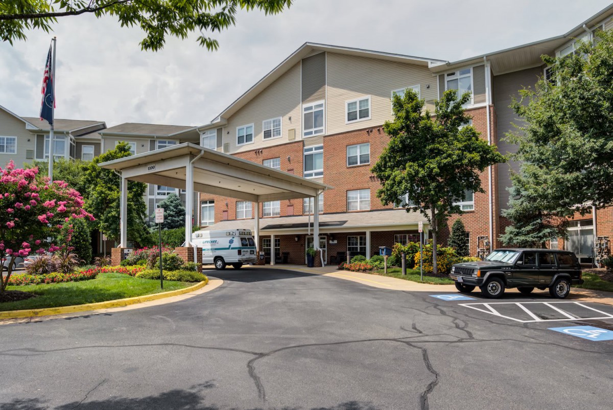 A residential building with a covered entrance and parked vehicles.