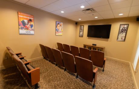 A cozy home theater setup with rows of seating and movie posters on the walls.