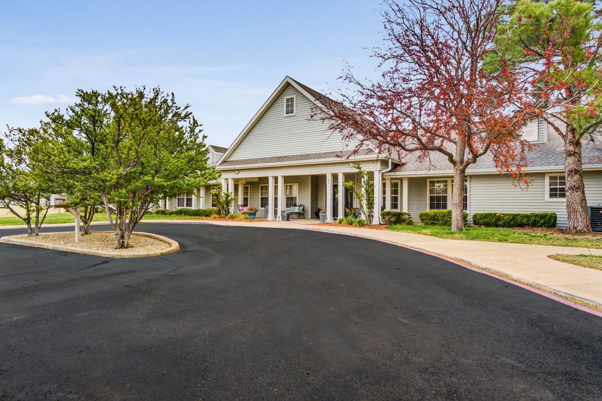 A residential building with a driveway and surrounding trees.