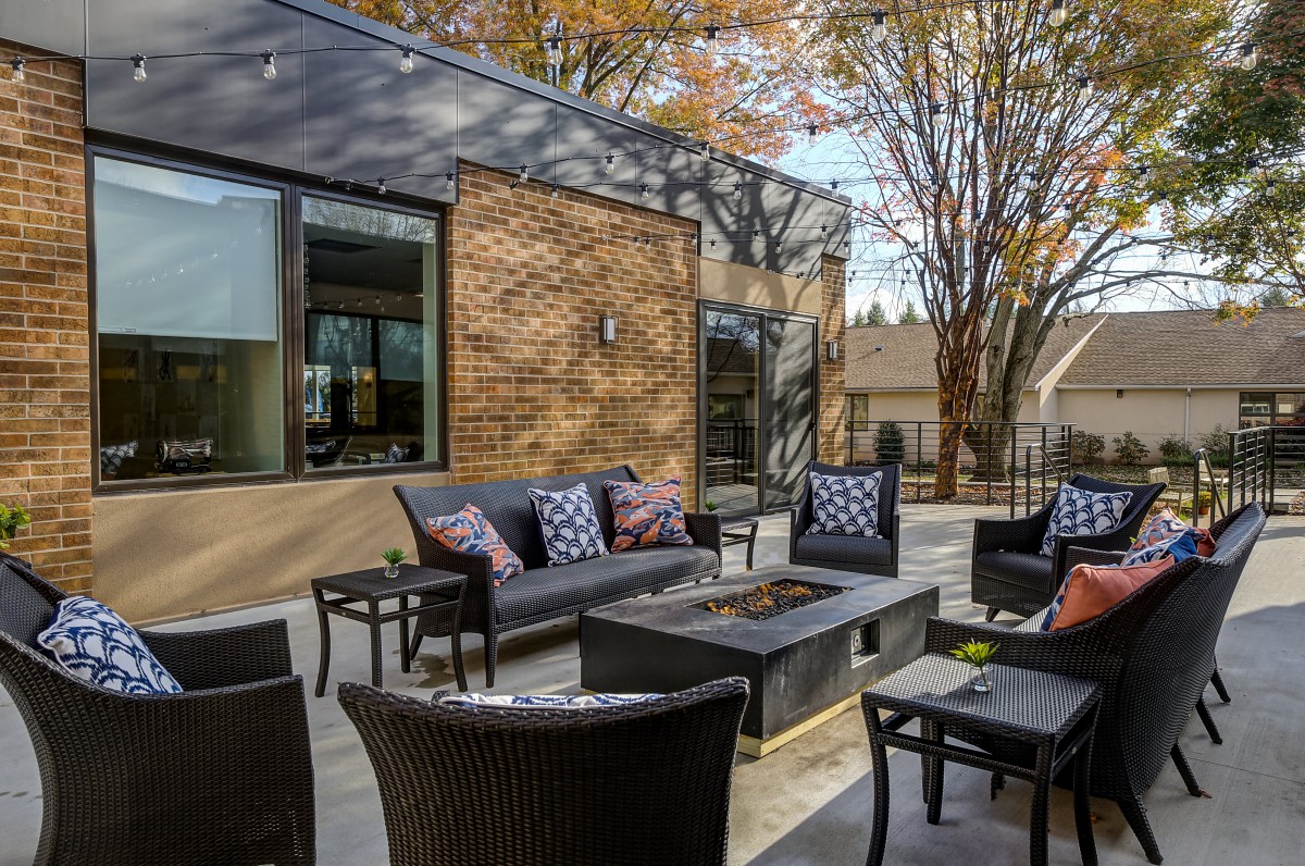 A modern outdoor patio with comfortable seating and a brick exterior.