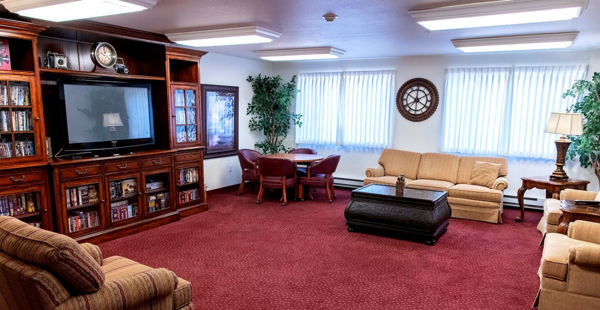 A cozy living room featuring a television, sofa, and coffee table with red carpet and decorative elements.