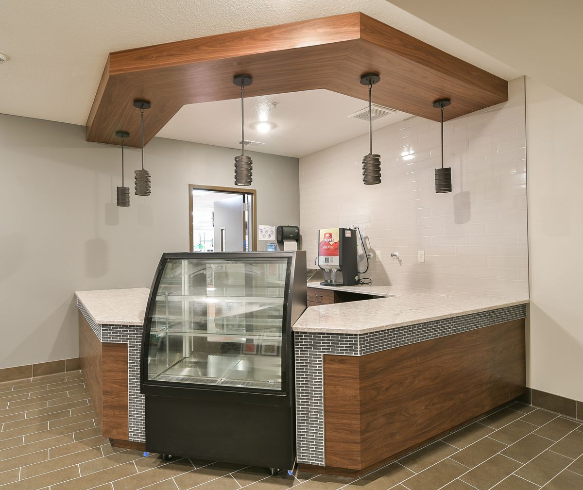 A modern cafe counter with a display case and pendant lighting.