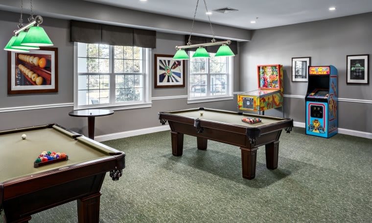 A cozy game room with a pool table, pinball machine, and stylish lighting.