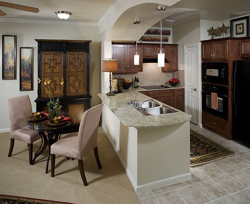 A modern kitchen with an adjacent dining area, featuring contemporary furnishings and elegant lighting.