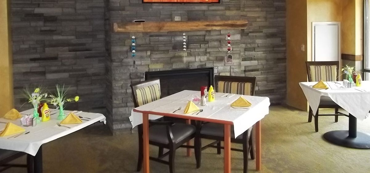 A cozy restaurant dining table set for two, with a rustic brick fireplace in the background.