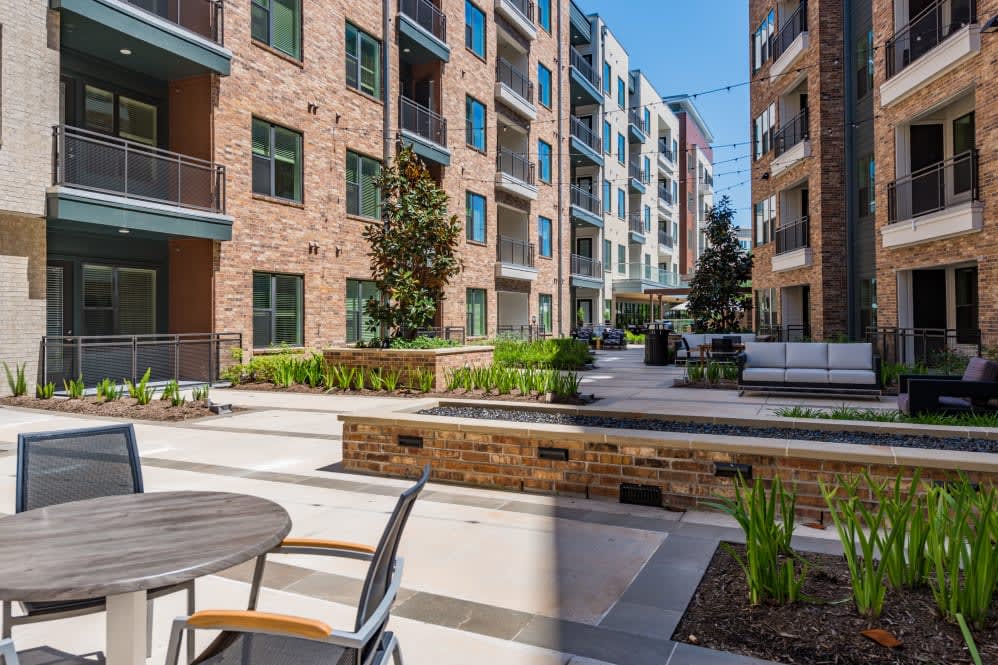 A modern apartment complex with outdoor seating and landscaped areas.