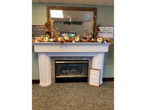 A cozy indoor fireplace adorned with autumn decorations and a large mirror above.