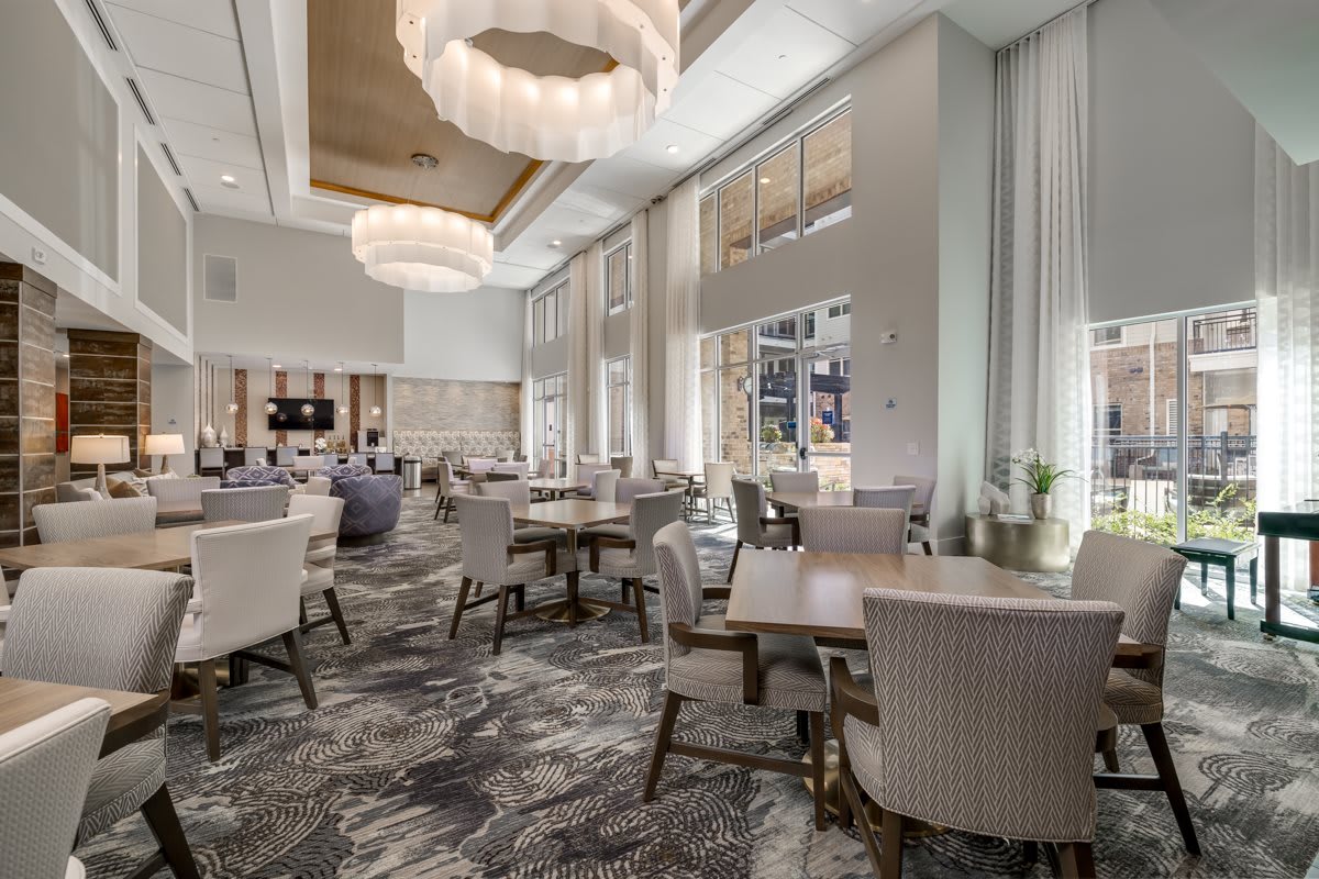 A modern and elegant restaurant interior featuring chic furniture and large chandeliers.