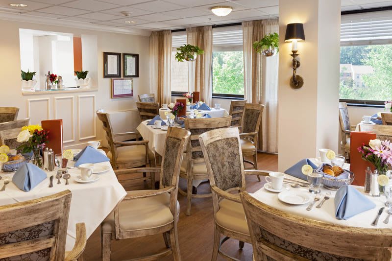 A cozy dining area with elegantly set tables and comfortable chairs by the windows.