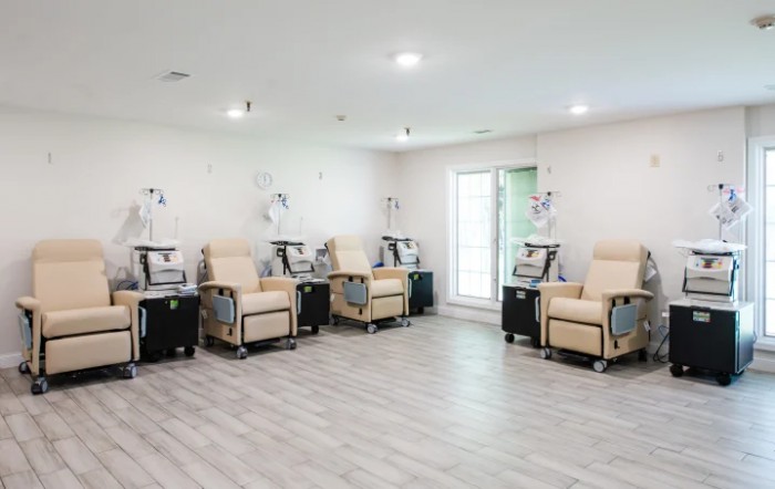 A modern infusion room with comfortable chairs and IV machines.