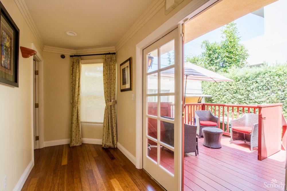 A cozy living room with hardwood floors opens to a sunny deck featuring outdoor furniture.