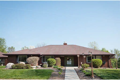 A charming single-story house with well-maintained landscaping and a clear blue sky.