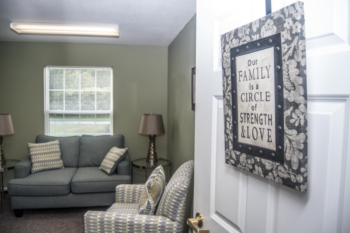 A cozy living room with a sign on the door that reads, 'Our Family is a Circle of Strength and Love'.