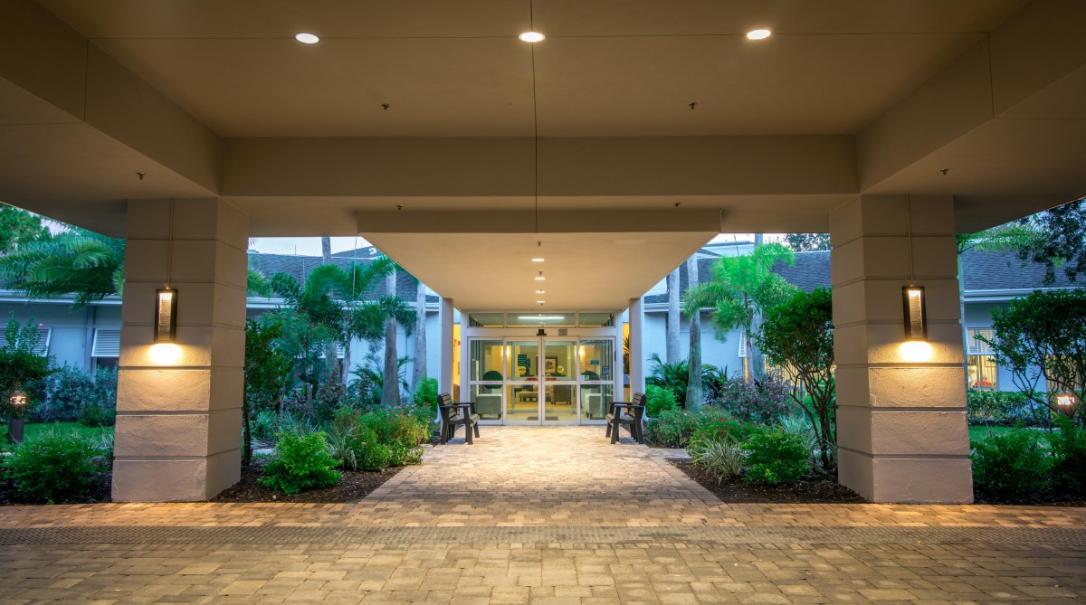 An illuminated entrance corridor with lush greenery on both sides.