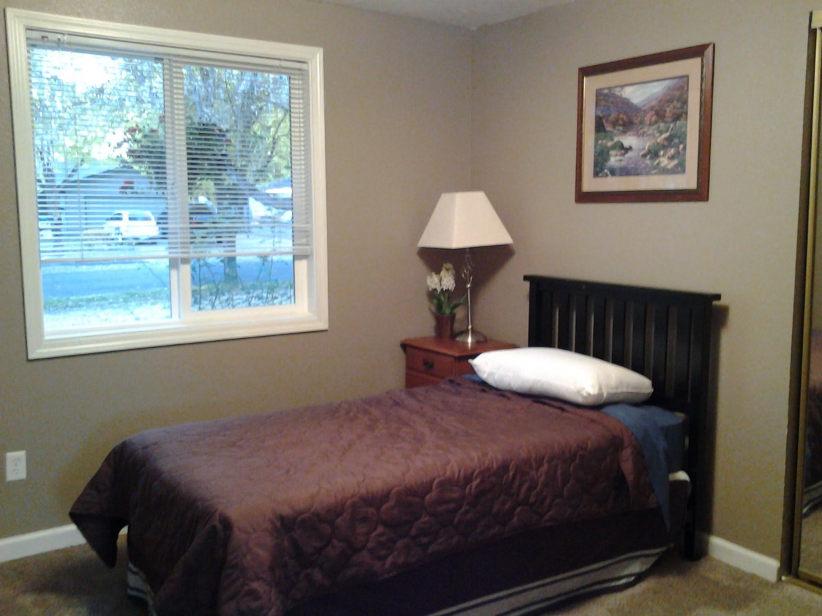 A cozy bedroom with a single bed, nightstand, and window.