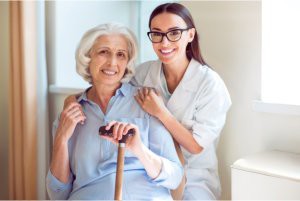 A caregiver smiling with an elderly woman at home.