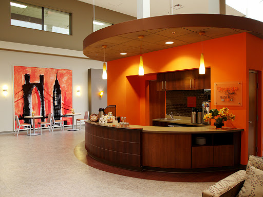 A modern reception area featuring an orange accent wall, wooden counters, and contemporary artwork.