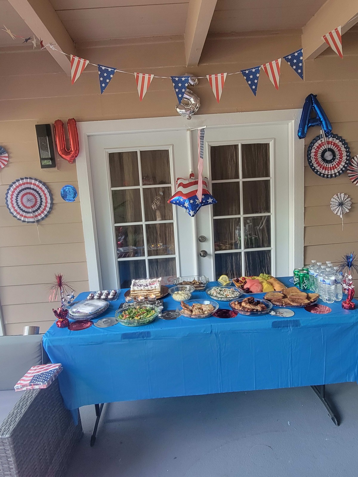 A festive table setup with patriotic-themed decorations and a variety of foods, ready for a party.