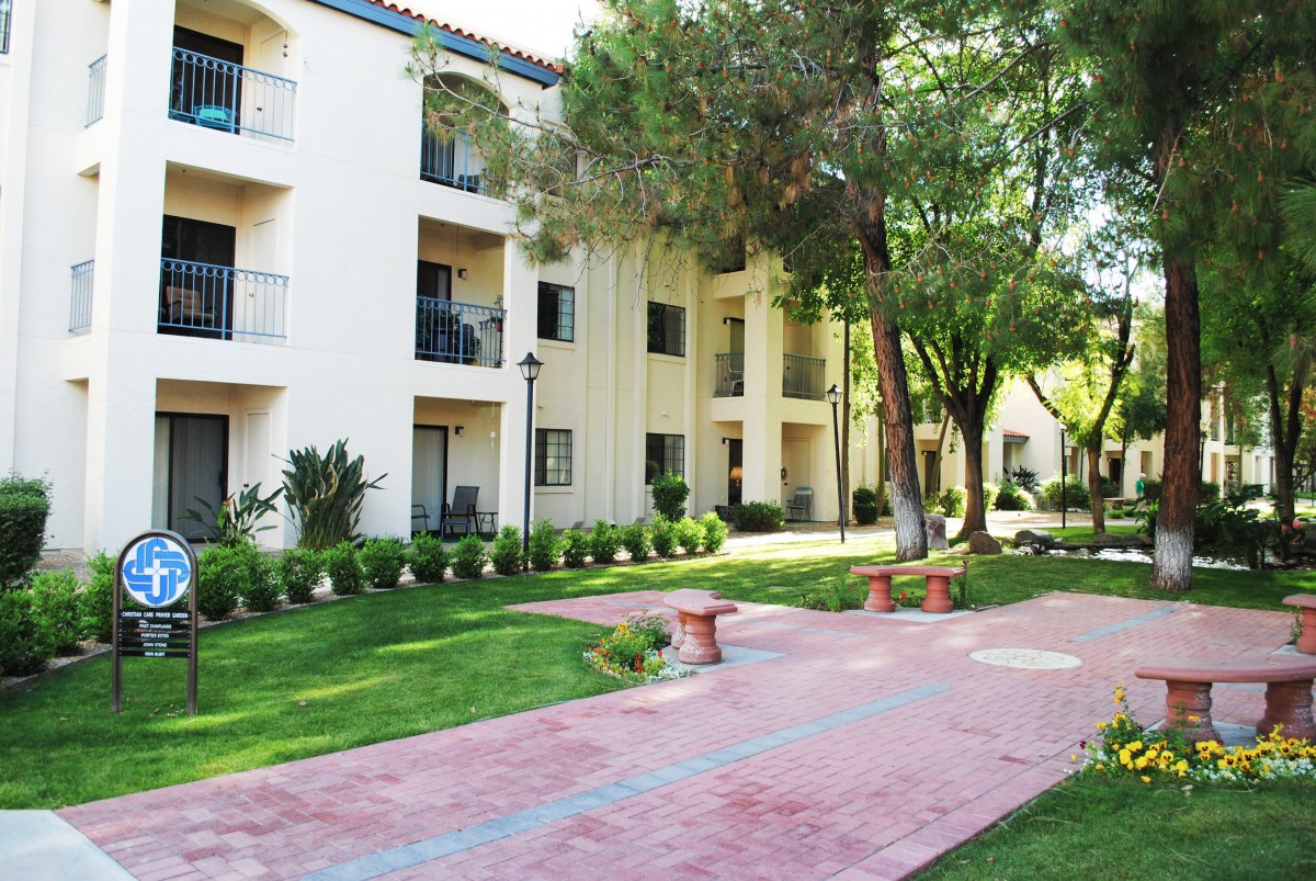 A well-maintained apartment complex with lush green surroundings and a paved walkway.
