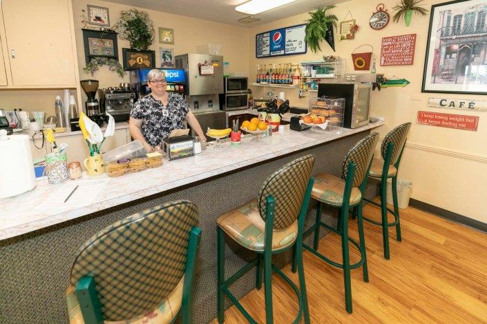 A cozy diner with a counter and seating, featuring a friendly staff member ready to serve.