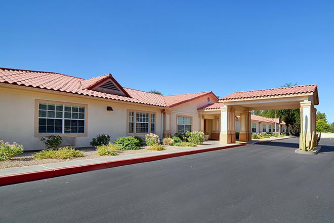 A single-story building with a prominent entrance and well-maintained landscaping under a clear blue sky.