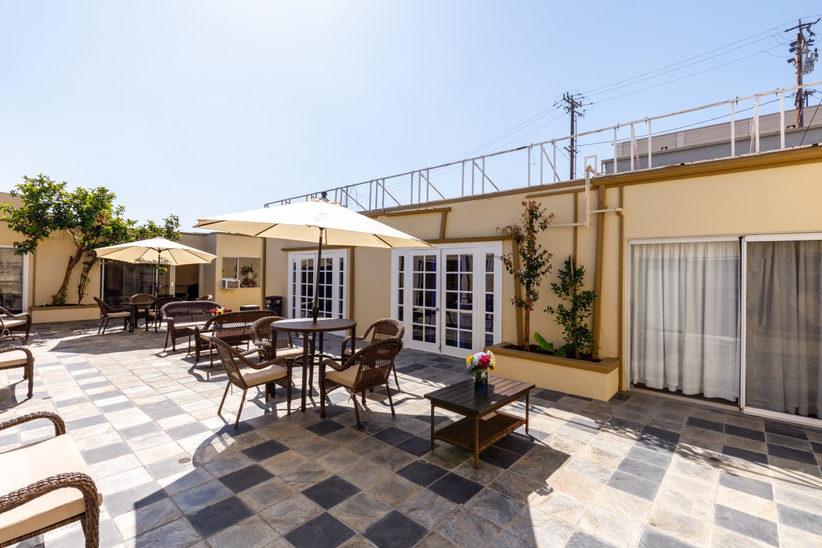 Sunny outdoor patio with tables, chairs, and umbrellas.