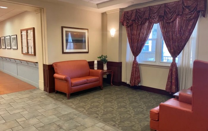 A cozy lobby seating area with red sofas, decorative curtains, and a framed painting on the wall.