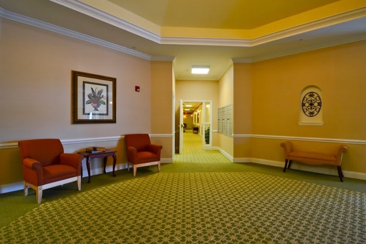 A warmly lit hallway with chairs and decorative paintings on the walls.