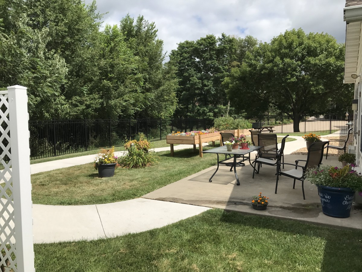 A peaceful backyard with a patio area, outdoor furniture, and lush greenery.