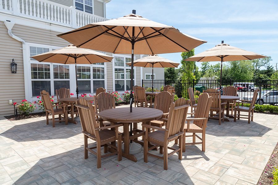A patio area with wooden tables and chairs under large umbrellas.