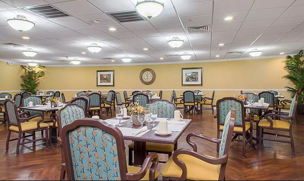An elegantly furnished dining room with neatly arranged tables and chairs, softly lit by overhead lamps.