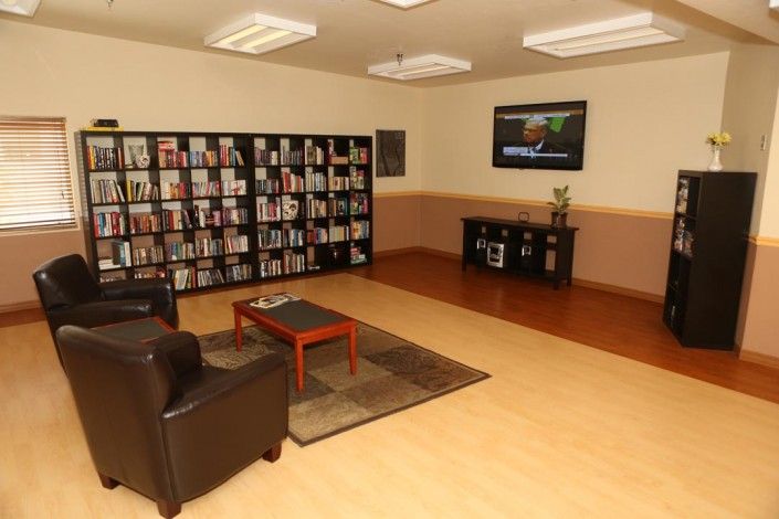 A cozy library corner with bookshelves, comfortable seating, and a television.