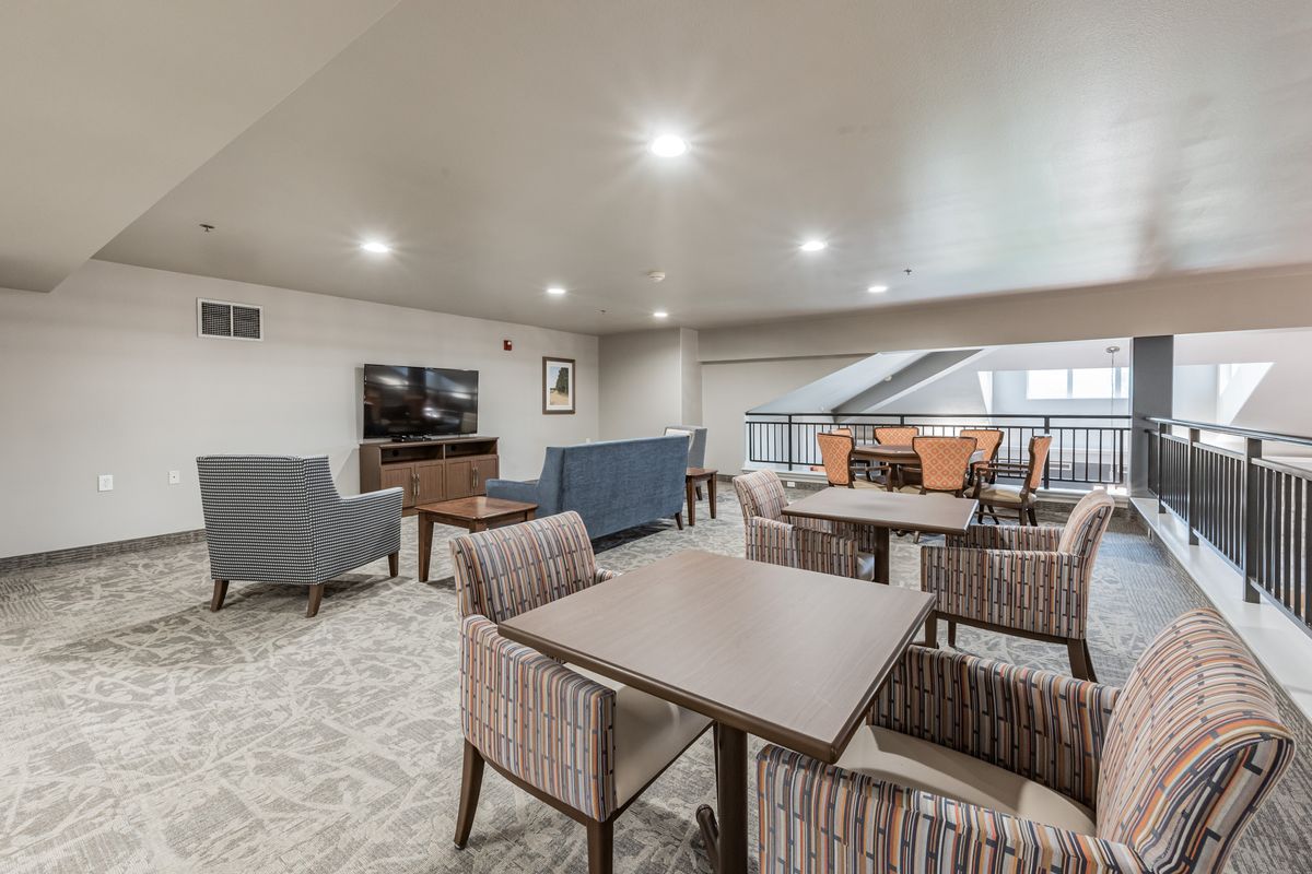 A modern lounge area with comfortable seating, a television, and a carpeted floor.