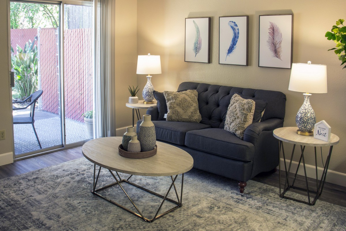 A modern living room with a dark sofa, decorative pillows, and a stylish coffee table in front of framed artwork.