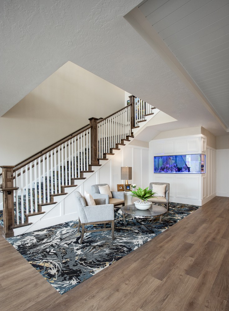 A modern living room with a stylish staircase, featuring elegant furniture and contemporary artwork.